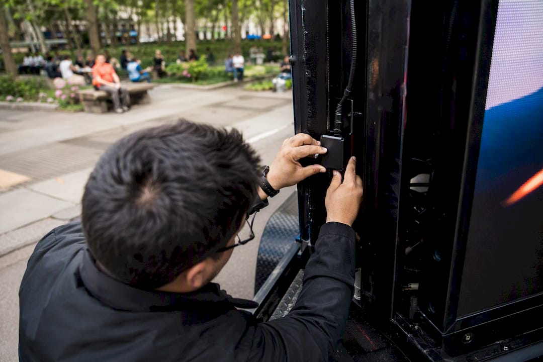 Hands installing GPS on mobile billboard truck